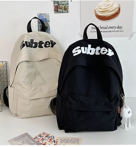 Dettaglio di zaini scolastici minimalisti con scritta Subtey e ciondolo di peluche