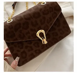 Close-up of leopard print shoulder bag with golden hardware lock and metal chain