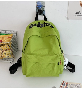 Dettaglio dello zaino in nylon verde con logo Subte, tag fashion e ciondolo di peluche
