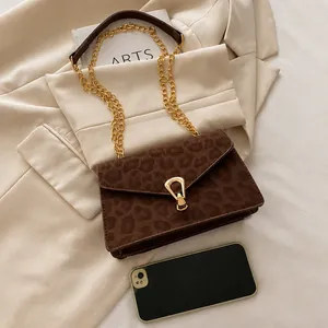 Detail of leopard print shoulder bag with gold metal clasp and chain strap
