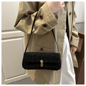 Détail du sac sous le bras léopard noir avec boucle dorée sur un trench-coat beige