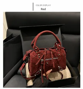 Detalle del bolso de estilo motero burdeos con remaches, borlas y cremalleras metálicas
