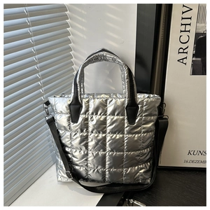 Détail du sac cabas matelassé argenté avec poignées noires et bandoulière réglable