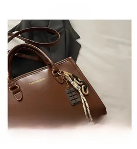 Détails du sac fourre-tout marron foncé avec logo doré, chaîne décorative et breloque chocolat