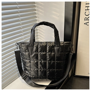 Détail d'un grand sac cabas matelassé noir avec bandoulière réglable et poignées