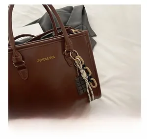Détail du sac à main en cuir verni marron foncé avec breloques et logo doré