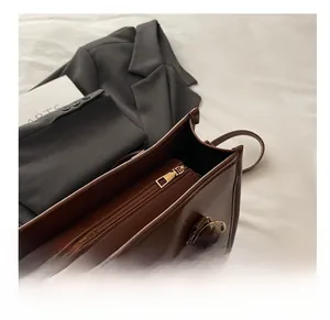 Détail du compartiment à fermeture éclair dorée sur un sac à main en cuir marron foncé