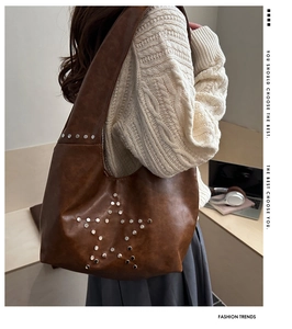 Dettaglio delle borchie a stella argentate e pelle marrone su borsa a spalla hobo