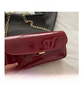 Detail view of burgundy patent leather baguette bag featuring a gold chain strap