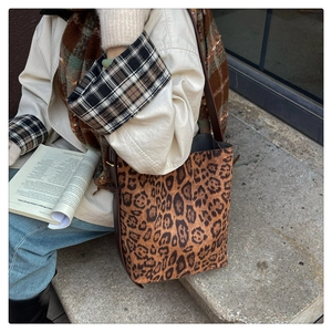 Detail of leopard print tote bag with brown straps styled on stone steps with a book