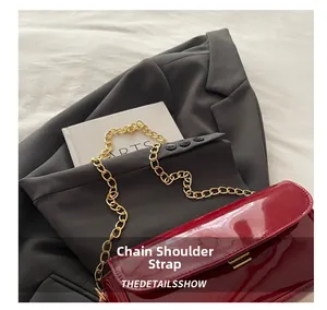 Detail of red oil wax leather shoulder bag with golden chain strap on stylish suit