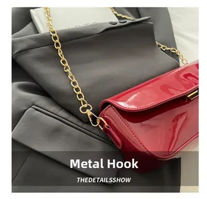 Close-up of dark red patent leather bag with gold metal chain and hardware hook