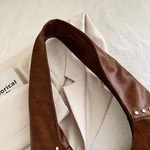 Détail de la bandoulière de sac en cuir ciré marron vintage avec rivets métalliques
