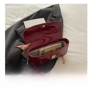 Macro view of the spacious burgundy patent leather bag interior with gold chain strap