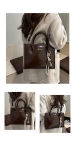 Détail d'un sac cabas en cuir verni marron foncé avec un pendentif chocolat et lettrage doré