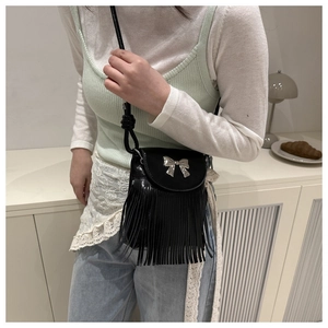Détail du sac bandoulière noir avec nœud en métal argenté et longues franges fluides
