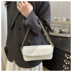 Detailed view of white patent leather baguette bag with gold chain strap on a model