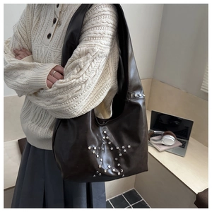 Dettaglio borsa a mezzaluna vintage in pelle marrone con borchie argentate a forma di stella
