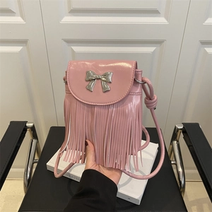 Sac à bandoulière rose avec boucle nœud argentée et longues franges sur livre blanc