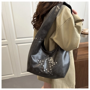 Détail du sac hobo noir avec motifs d'étoiles en rivets argentés et large bandoulière