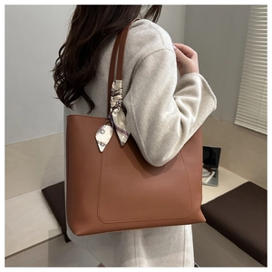 Détail du sac cabas en cuir marron avec couture en U et foulard en soie décoratif sur l'anse