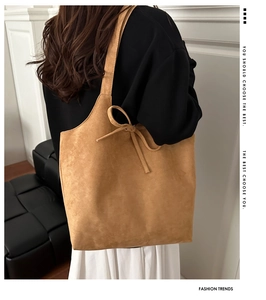Close-up of large camel suede tote bag with stylish bow knots on the shoulder strap