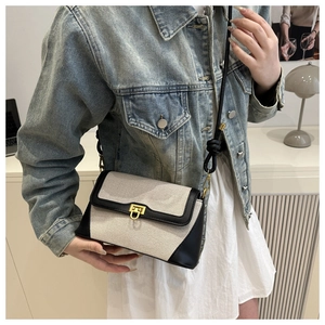 Detail view of contrast stitch shoulder bag with gold clasp on denim jacket outfit