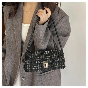 Detail of tweed shoulder bag with yellow plaid texture and gold twist-lock clasp
