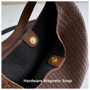 Detail shot of the golden magnetic snap closure and woven texture on a brown tote bag