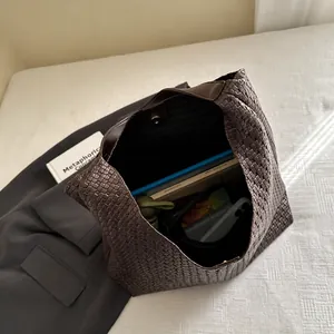 Macro view of a large brown woven tote bag interior showing spacious storage and magnetic closure