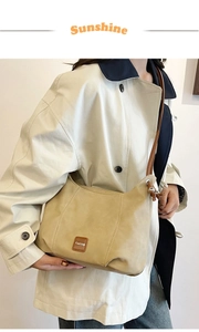 Détail du sac bandoulière en cuir kaki avec écusson logo et coutures contrastées