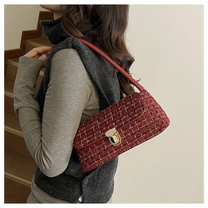 Detail of burgundy tweed shoulder bag featuring a vintage gold metal clasp and chain strap