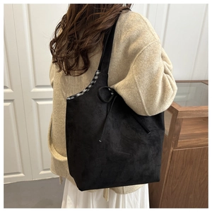 Detail of black suede tote bag with side bow and classic black and white checkered lining