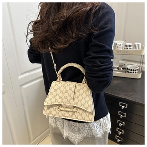 Detail of crossbody bag with brown M print and beige leather texture worn by model