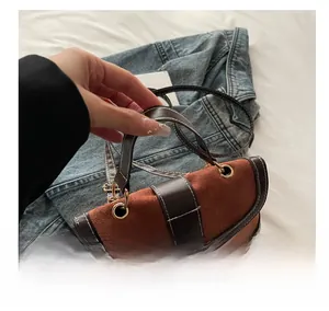 Detail of vintage suede bag with brown leather trim and golden circular metal clasp