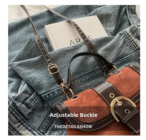 Close-up of caramel suede handbag with golden horseshoe buckle and white stitching details