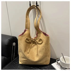 Detail of tan suede tote bag with a decorative bow and red checkered fabric lining