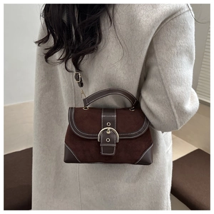 Detail of vintage brown suede crossbody bag with metal buckle on grey wool coat