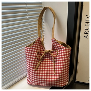Detail of red and white checkered tote bag with brown suede bow and wide base
