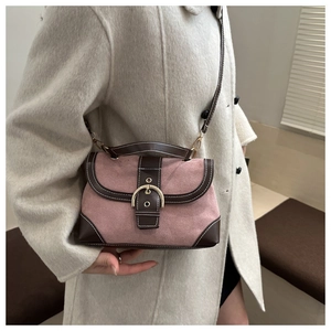 Detail of pink suede handbag with brown leather trim and metallic buckle on beige coat