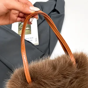 Detail van bruine pluche handtas met leren handvat en wit contrasterend stiksel