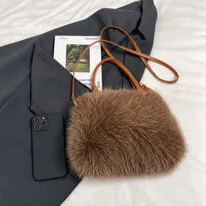 Detail van bruine pluche schoudertas met lederen riem en smartphone voor de grootte-indicatie
