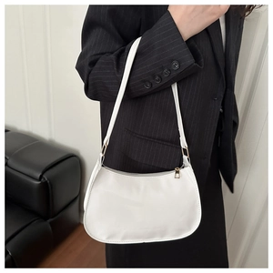 Detailed close-up of a white patent leather shoulder bag with gold metal zipper