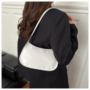 White glossy patent leather baguette bag shown as worn by a model in a minimalist setting