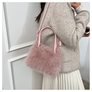 Detailansicht der rosa Kunstfell-Handtasche mit Ledergriff und verstellbarer Metallschnalle