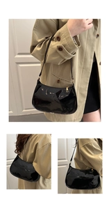 Détail du sac baguette en cuir verni noir brillant avec des finitions dorées chics
