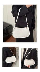 Détail du sac baguette en cuir verni blanc avec fermeture éclair dorée et design épuré
