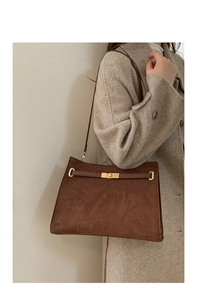Gros plan du sac cabas en daim marron avec fermoir tournant doré et lanière en cuir