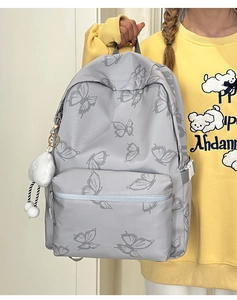 Detail of light gray butterfly print backpack with plush charm and side buckle strap