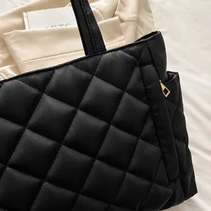 Gros plan du sac fourre-tout noir matelassé avec coutures losanges et zip doré